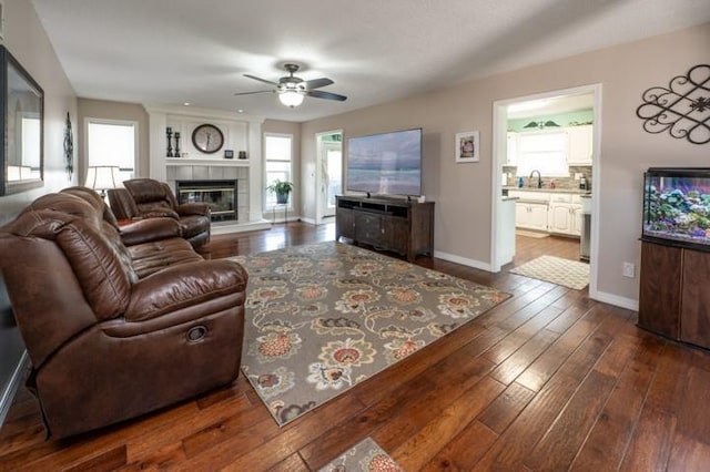 6620 NW 136th St, Kansas City, MO 64164 - living room with dark wood-type flooring, a tiled fireplace, a ceiling fan, and plenty of natural light