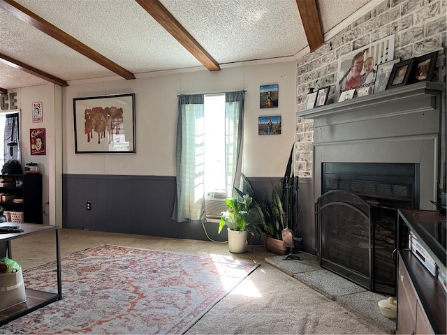 carpeted living room with a fireplace, a textured ceiling, beam ceiling, cooling unit, and wainscoting