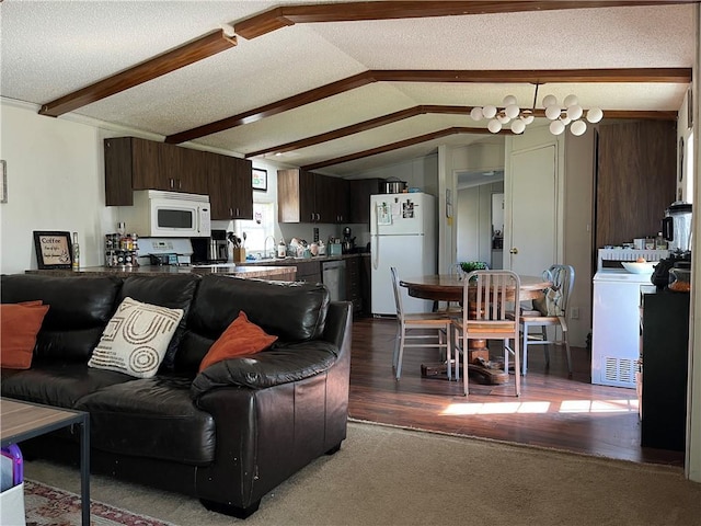 living area featuring washer / clothes dryer, dark wood-style flooring, a textured ceiling, and vaulted ceiling with beams