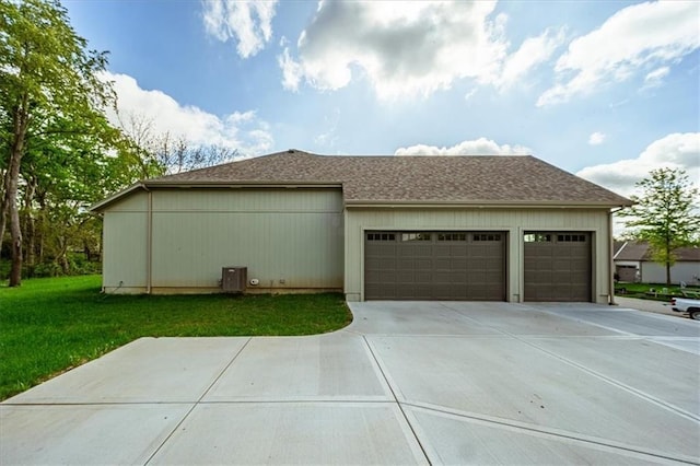view of side of property with an attached garage, a shingled roof, a lawn, and driveway