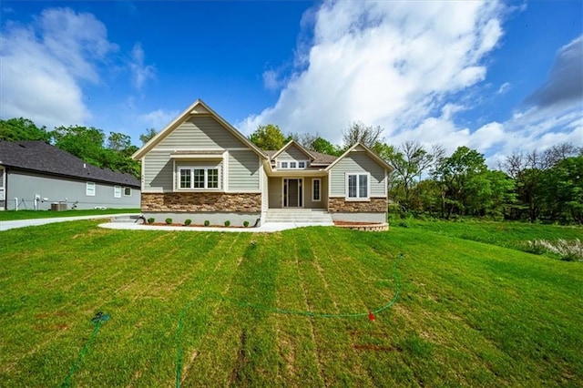 back of house with a lawn and stone siding