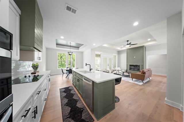 kitchen featuring visible vents, a sink, light countertops, green cabinetry, and a tray ceiling