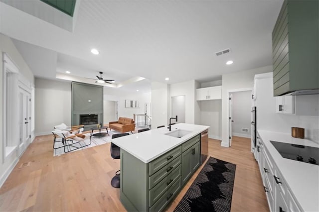 kitchen featuring visible vents, a ceiling fan, black electric stovetop, a sink, and green cabinets