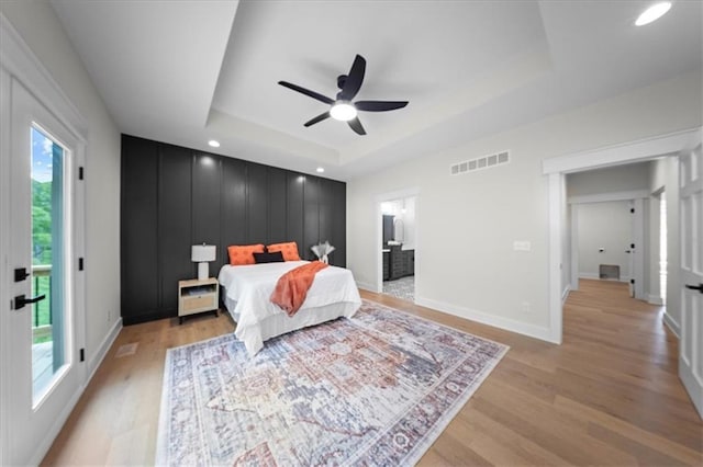 bedroom with visible vents, a raised ceiling, baseboards, light wood-style floors, and recessed lighting