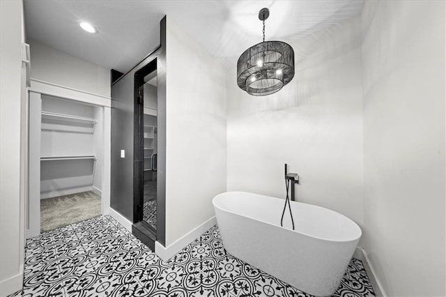 bathroom with a walk in closet, a freestanding tub, a stall shower, baseboards, and a notable chandelier