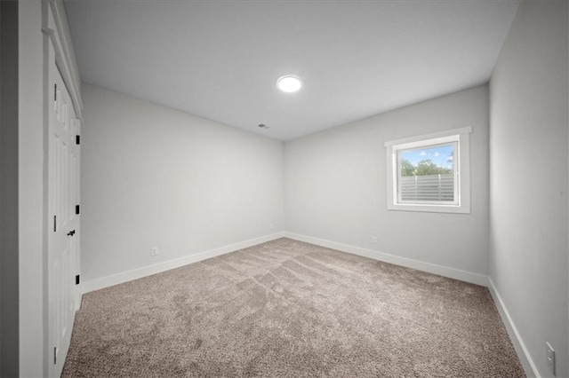 carpeted spare room featuring baseboards