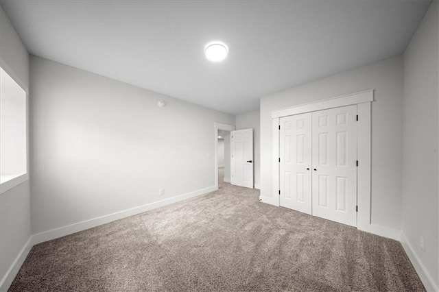 unfurnished bedroom with baseboards, carpet flooring, and a closet