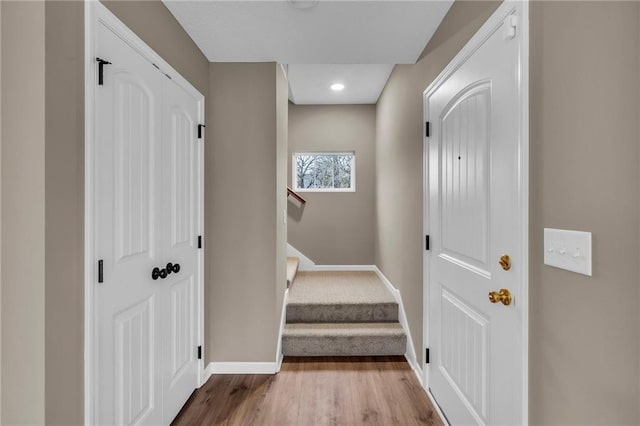 corridor featuring baseboards, wood finished floors, and stairway