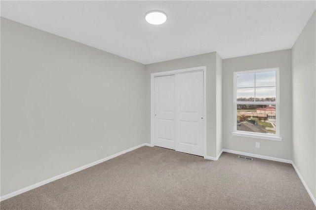 unfurnished bedroom with carpet flooring, baseboards, and visible vents