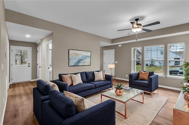 living room with baseboards, a textured ceiling, ceiling fan, and wood finished floors
