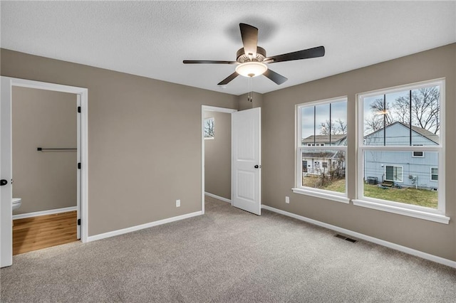 unfurnished bedroom featuring carpet flooring, a textured ceiling, baseboards, and visible vents