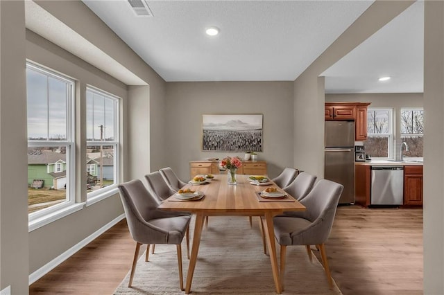 dining space with recessed lighting, baseboards, light wood finished floors, and visible vents