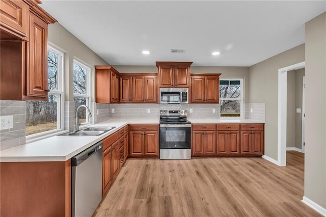 kitchen featuring a sink, brown cabinetry, light wood-style flooring, and appliances with stainless steel finishes