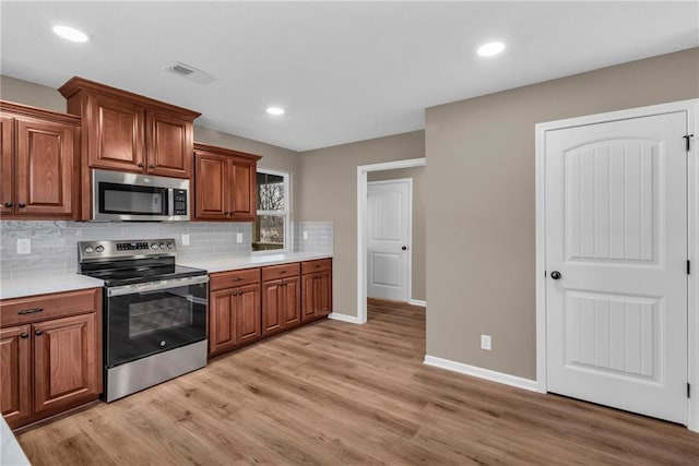 kitchen with light wood-style flooring, visible vents, stainless steel appliances, and tasteful backsplash