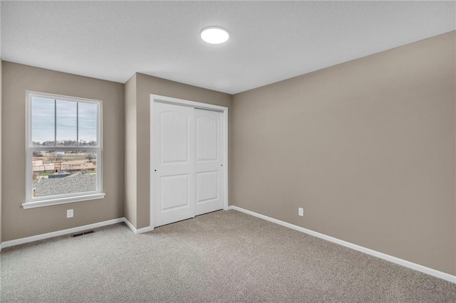 unfurnished bedroom with a closet, carpet, baseboards, and visible vents