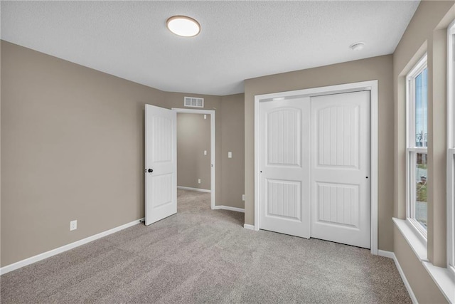 unfurnished bedroom with a closet, baseboards, visible vents, and multiple windows