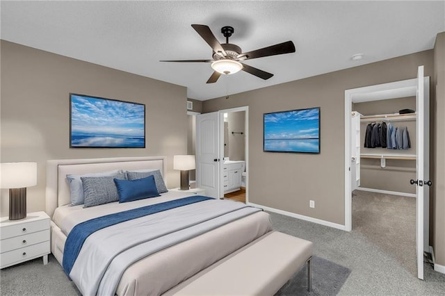 bedroom featuring a closet, a walk in closet, carpet, and baseboards