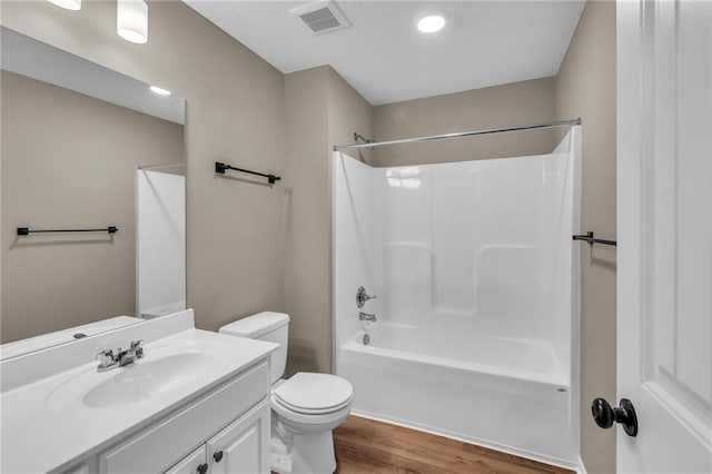 bathroom with vanity, toilet, visible vents, shower / bathtub combination, and wood finished floors