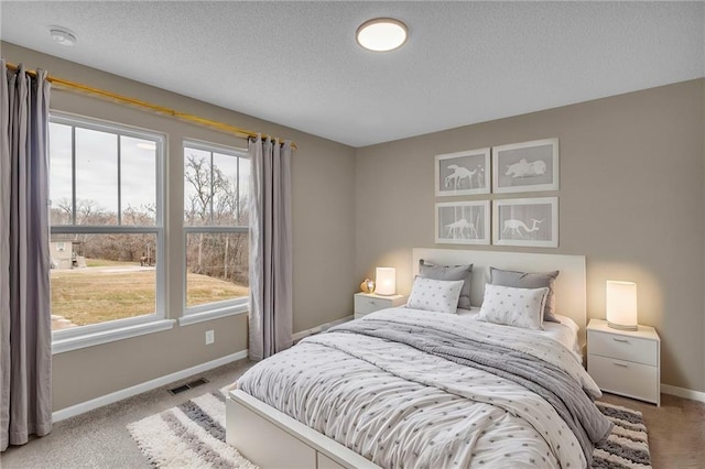carpeted bedroom with a textured ceiling, baseboards, and visible vents