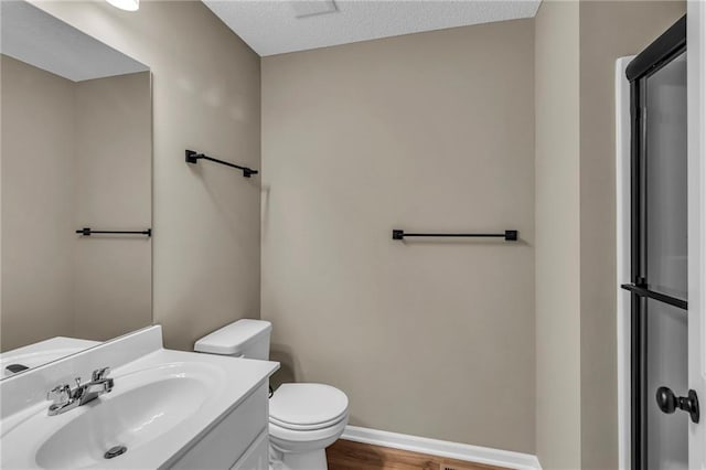 bathroom with baseboards, toilet, vanity, and wood finished floors