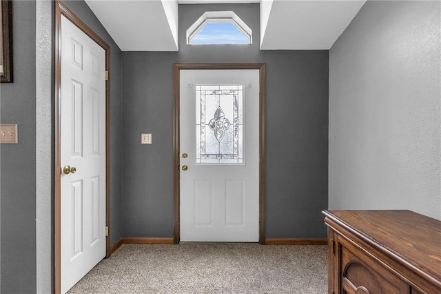 foyer entrance featuring baseboards and light carpet