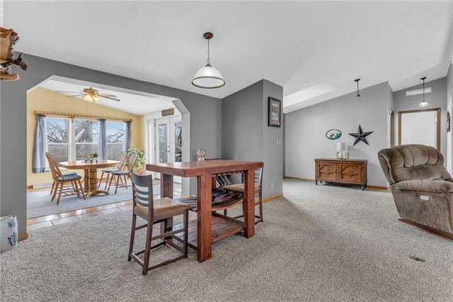 dining area featuring light colored carpet, lofted ceiling, a ceiling fan, and baseboards