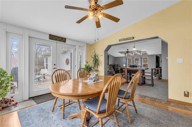 dining space featuring french doors, vaulted ceiling, baseboards, a ceiling fan, and wood finished floors