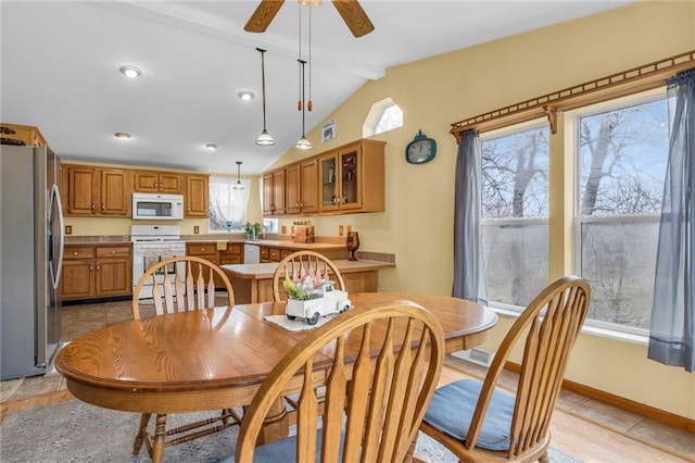 dining space featuring plenty of natural light, a ceiling fan, vaulted ceiling with beams, and baseboards