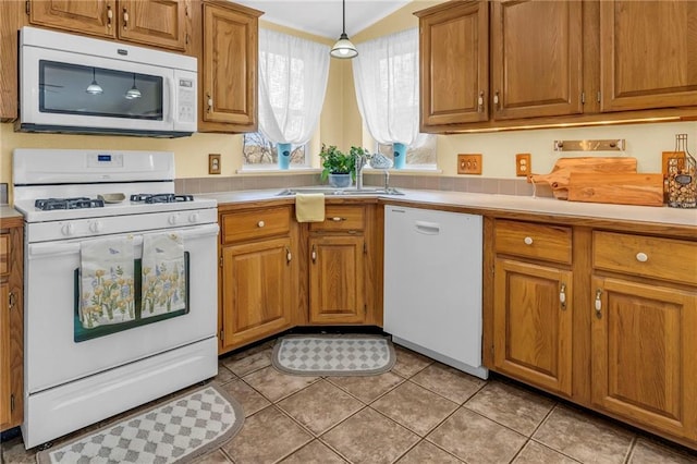 kitchen with brown cabinetry, light countertops, and white appliances
