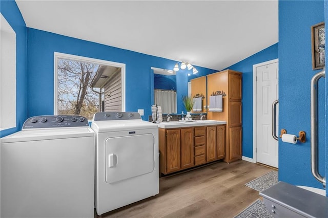 laundry area with washing machine and clothes dryer and light wood-type flooring