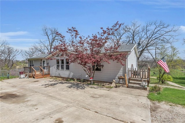 exterior space with driveway, fence, and a deck