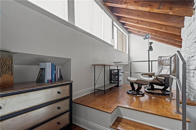 living area with baseboards, vaulted ceiling with beams, and wood finished floors