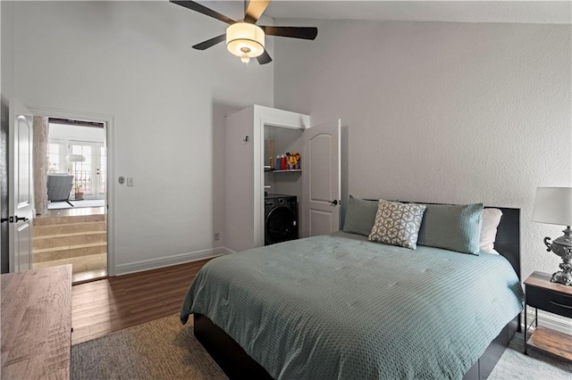 bedroom featuring ceiling fan, high vaulted ceiling, washer / clothes dryer, baseboards, and wood finished floors
