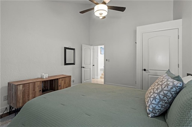 bedroom with baseboards, ceiling fan, and a towering ceiling