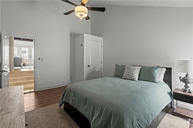bedroom featuring baseboards, ceiling fan, wood finished floors, and high vaulted ceiling