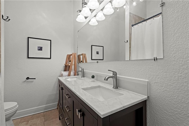 full bathroom featuring double vanity, toilet, a chandelier, and a sink
