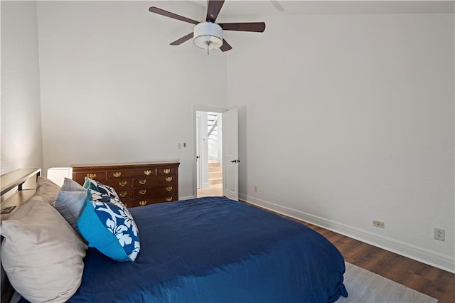 bedroom featuring baseboards, a ceiling fan, a towering ceiling, and wood finished floors