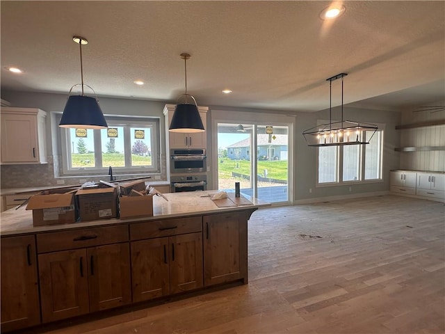 2005 Foxtail Pt, Kearney, MO 64060 - kitchen featuring double oven, light wood finished floors, decorative backsplash, recessed lighting, and a center island