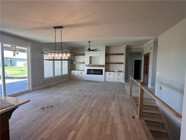 2005 Foxtail Pt, Kearney, MO 64060 - unfurnished living room featuring a textured ceiling, wood finished floors, a fireplace, and a ceiling fan