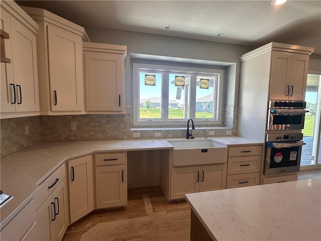 2005 Foxtail Pt, Kearney, MO 64060 - kitchen with backsplash, light wood-type flooring, light stone counters, and double oven