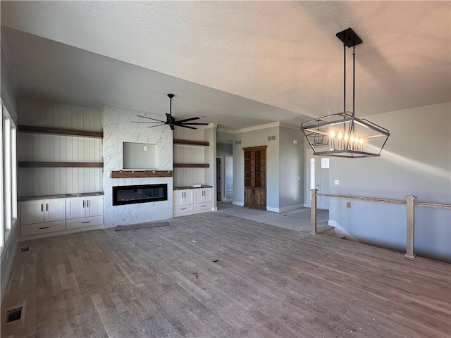 2005 Foxtail Pt, Kearney, MO 64060 - unfurnished living room featuring wood finished floors, a fireplace, a chandelier, ceiling fan, and a textured ceiling