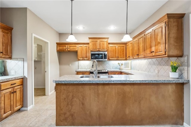 kitchen featuring pendant lighting, stainless steel microwave, tasteful backsplash, a sink, and brown cabinetry