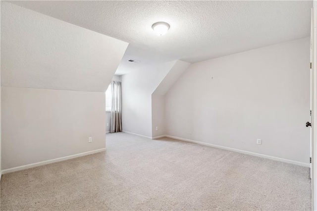 bonus room featuring lofted ceiling, a textured ceiling, carpet flooring, and baseboards