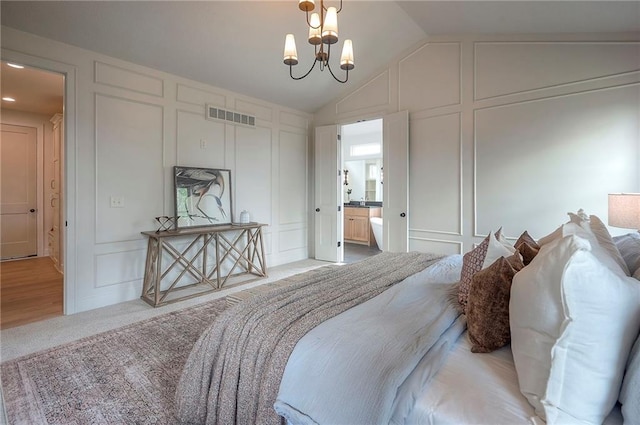 bedroom with visible vents, ensuite bathroom, vaulted ceiling, a decorative wall, and a notable chandelier