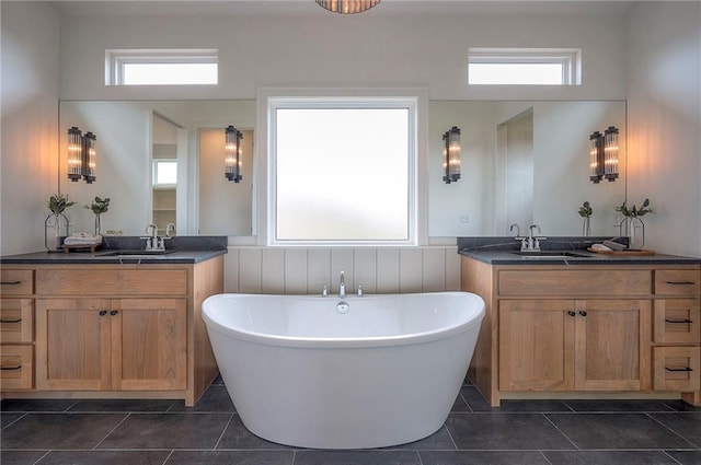 full bathroom with two vanities, a freestanding bath, tile patterned flooring, and a sink