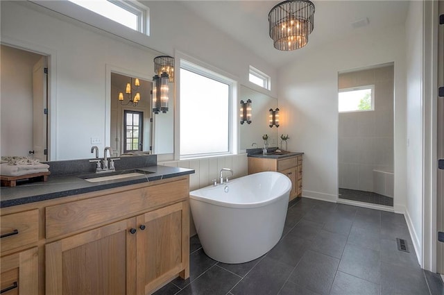 full bath featuring a sink, visible vents, a freestanding bath, two vanities, and a notable chandelier