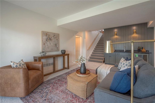 carpeted living room featuring stairs, baseboards, and beverage cooler