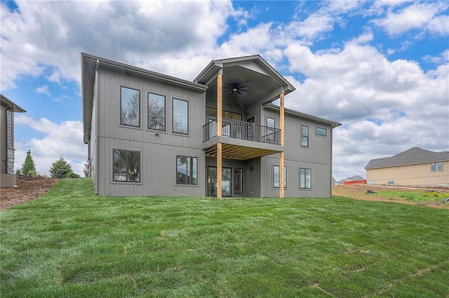 rear view of property featuring a balcony, a ceiling fan, and a lawn