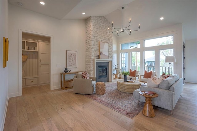 living area featuring a notable chandelier, light wood-type flooring, high vaulted ceiling, and baseboards