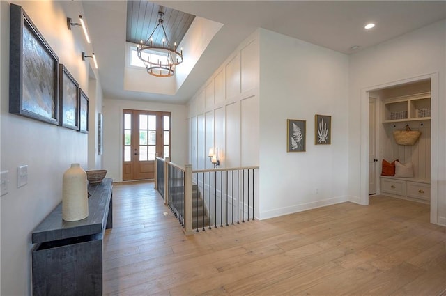 hall with light wood-style flooring, an upstairs landing, baseboards, recessed lighting, and a notable chandelier